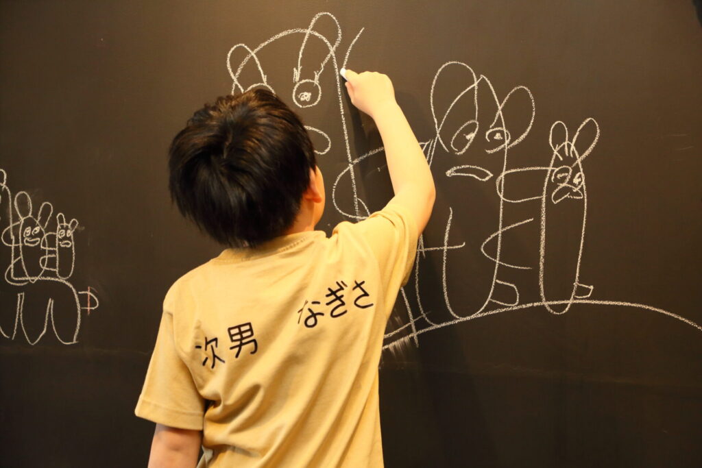 店内に設置している大きな黒板に小さな男の子が寄せ書きをしている様子